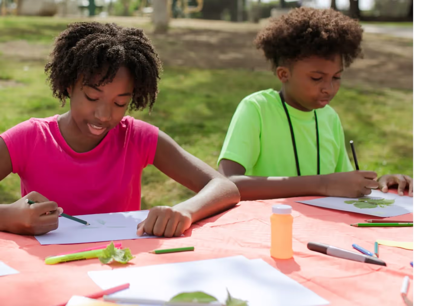 A couple of kids sitting at a table with paper